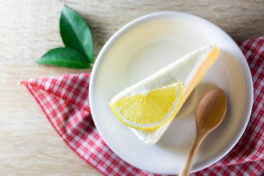 Ahşap masa üzerinde dekoratif arka planı olan beyaz tabakta bir parça turuncu pasta.