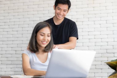 Evde dizüstü bilgisayarla çalışan genç ve gülümseyen bir çiftin portresi rahatlatan bir kızın omuzuna masaj yapmak.