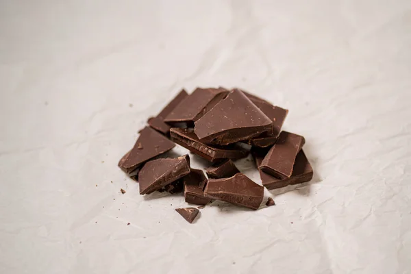 白いベーキング紙の上の壊れたダークチョコレートバー 甘い御馳走 — ストック写真