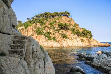 Kıyı uçurumun içinde yıkılmasını adımları ile. Arka planda başka bir taş, güneş tarafından aydınlatılmış olduğunu.