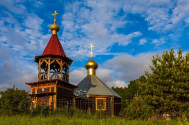 Yeşil bir orman ve bulutlu gökyüzünün arka planında pitoresk ahşap kilise