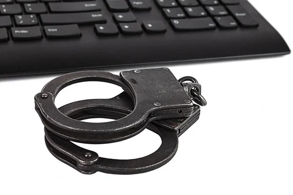 Police handcuffs and computer keyboard on white background