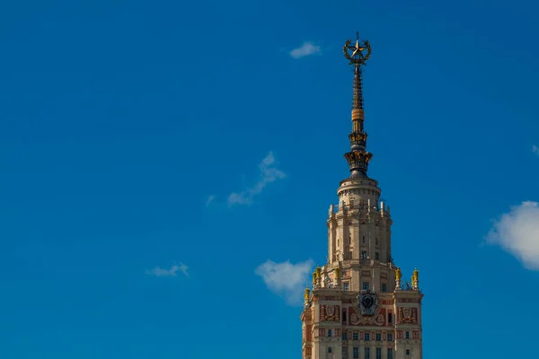 The spire of the Moscow University building on a background of blue sky in light clouds