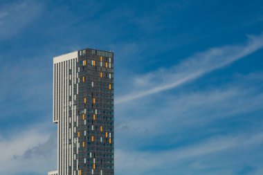 Cam ve betondan yapılmış modern bina, mavi gökyüzünün arka planında renkli eklentiler var.