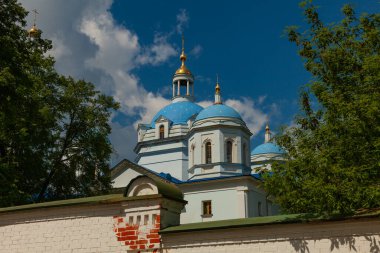 Orthodox church with blue domes and golden crosses. The church is surrounded by a stone fence.