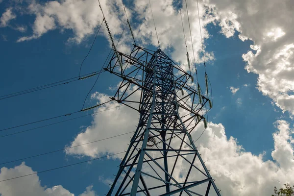 New pylon of electric transmission line in blue against a cloudy sky. Electric wires go from the support of the electric transmission line in different directions