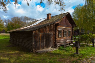 An old blackened from time log Russian house stands among trees