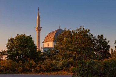Batan güneşin ışınlarıyla aydınlatılan yüksek minareli beyaz camii.