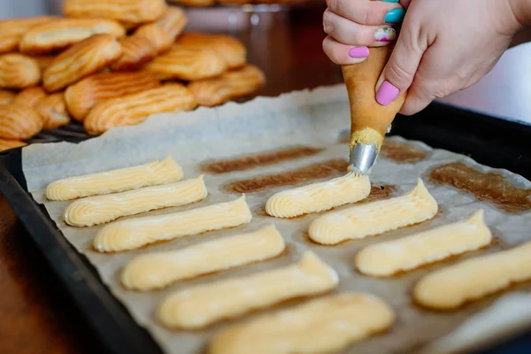Ev yapımı eklerleri. Eklerleri ev mutfakta hazırlanması. Eklerleri pişirme süreci. Pasta bir küçük, yumuşak, günlük şeklinde Pasta krema ile doldurulmuş ve genellikle çikolata sosu ile tepesinde.