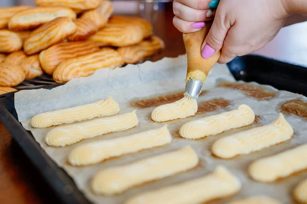 Homemade eclairs. Preparation of eclairs in the home kitchen. The process of cooking eclairs.Eclair a small, soft, log-shaped pastry filled with cream and typically topped with chocolate icing.