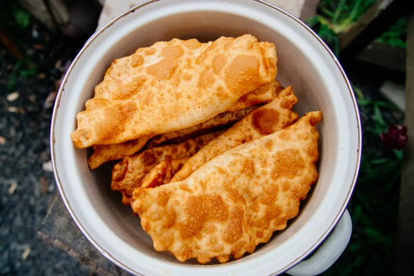 Chebureks pişirme süreci. Beyaz ve Doğu doldurulmuş kuzu ve baharatlı çeşnilikler ile ince mayasız hamur yapılmış bir patty besindir. Cheburek - et ve soğan ile kızarmış pasta.