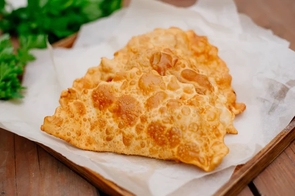 Chebureks pişirme süreci. Beyaz ve Doğu doldurulmuş kuzu ve baharatlı çeşnilikler ile ince mayasız hamur yapılmış bir patty besindir. Cheburek - et ve soğan ile kızarmış pasta.