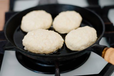 Peynirli kekler dökme demir bir tavada kızartılır. Kadın peynirli kek heykeli yapıyor. Peynirli kekler ev mutfağında pişirilir..