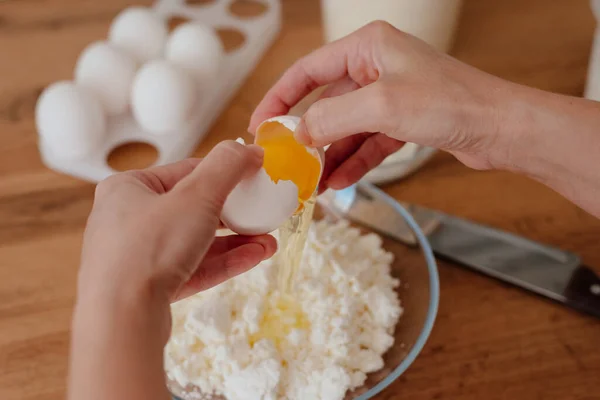 Peynirli krep. Ev mutfağında cheesecake yapma süreci. Bir kase süzme peynir, bir kadın süzme peyniri bir kaseye dolduruyor ve yumurta sürüyor. Süzme peynir ve yumurta sarısı.