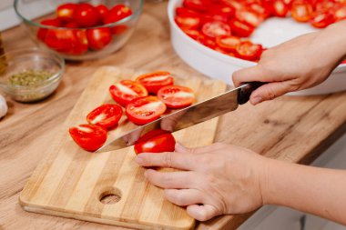 Güneşte kurutulmuş domates. Güneşte kurutulmuş domates pişirme işlemi. Kadın mutfakta domates hazırlıyor. Bir kadın domates keser, yağlar ve baharatlandırır.. 