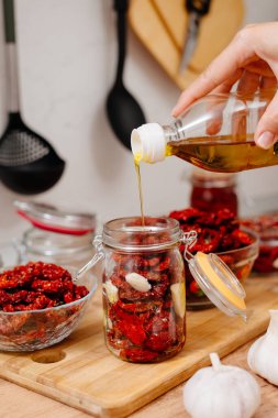 Güneşte kurutulmuş domates. Güneşte kurutulmuş domates pişirme işlemi. Kadın mutfakta domates hazırlıyor. Bir kadın domates keser, yağlar ve baharatlandırır.. 
