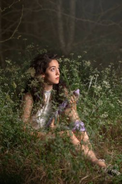 Güzel genç bir kadın karanlık bir ormanda poz veriyor. 