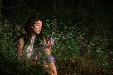 Güzel genç bir kadın karanlık bir ormanda poz veriyor. 