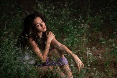 Güzel genç bir kadın karanlık bir ormanda poz veriyor. 