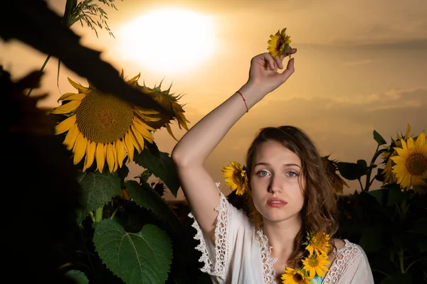 美しいです若いです女の子ポーズで夕日でひまわり畑 — ストック写真