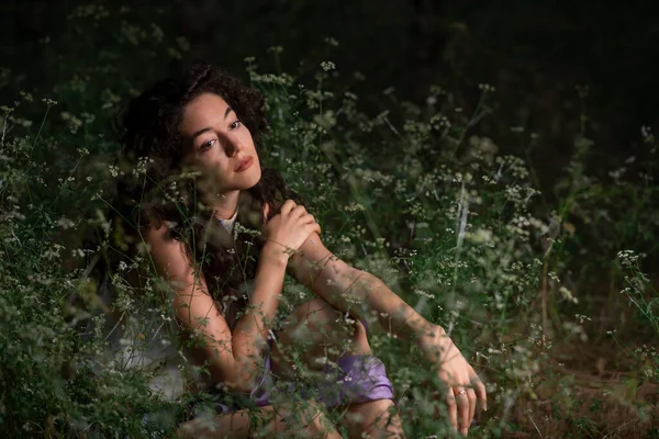 Güzel genç bir kadın karanlık bir ormanda poz veriyor. 