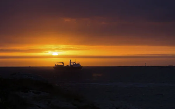 Red sun over the horizon, ship on the sea