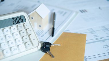 Beyaz hesap makinesi, finansal belgeler ve anahtarlı ev modeli mortgage sözleşmesi, ev kredisi ve gayrimenkul planlamasını temsil ediyor.
