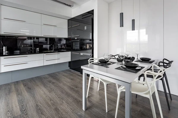 Beyaz masa, siyah duvar karoları ve yeni tasarım sandalyeler ile mutfak