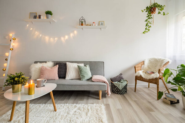 Sofa, coffee table and wicker chair in living room styled scandinavian