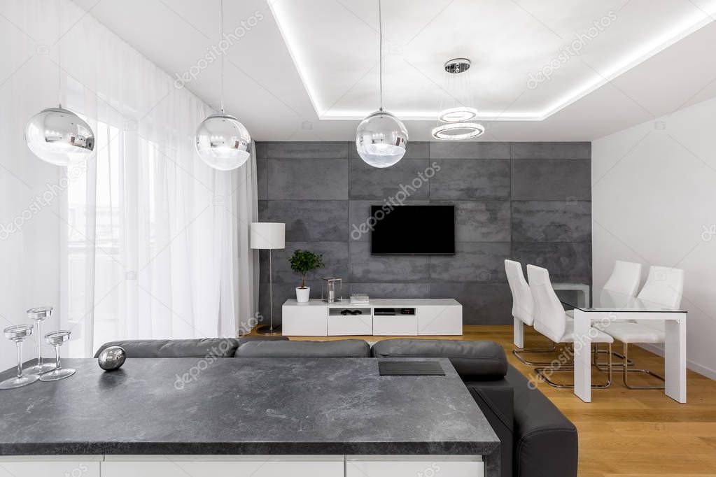 Modern, open plan apartment with concrete wall, lamps, tv, table and chairs