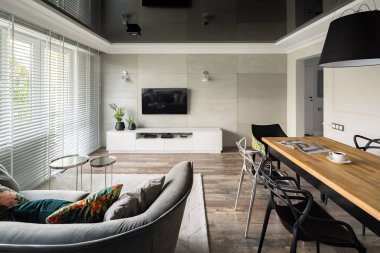 Tv living room with modern sofa, wooden table and black stretch ceiling