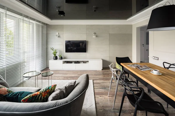 Tv living room with modern sofa, wooden table and black stretch ceiling