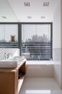 Beyaz banyo, büyük pencerenin altında küvet.