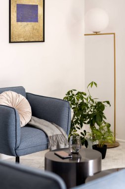 Modern mavi koltuk, oturma odasının köşesinde gri yastık ve battaniye.