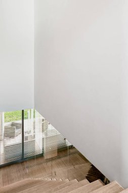 Ahşap merdivenli ev koridoru, panjurlu pencere ve büyük beyaz duvar.