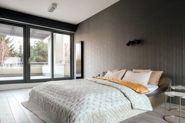 Çift kişilik yataklı şık bir yatak odası, pencere arkasında duvar kâğıdı ve balkon.