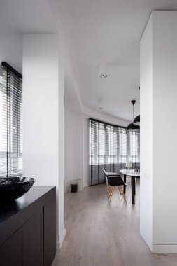 Açık dairede yemek odası ve koridor kıvrımlı duvarlı ve panjurlu bir sürü pencereli.