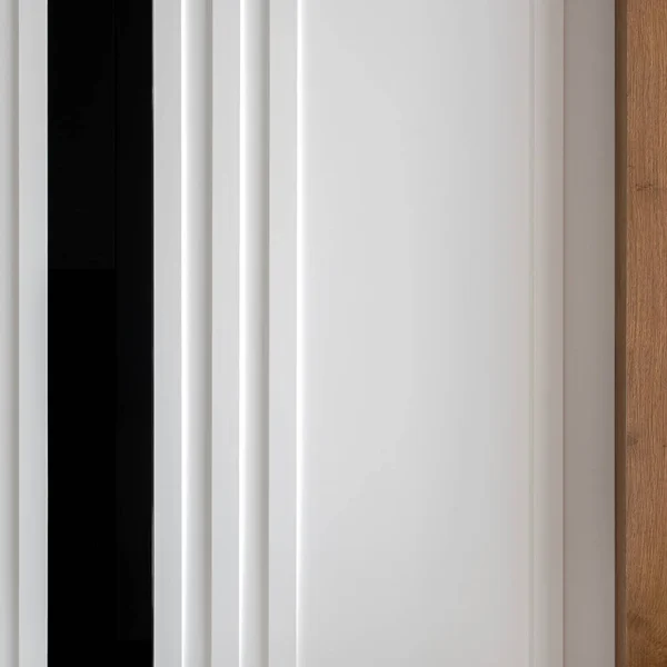 Close-up on elegant and decorated wall with white molding, black gloss panel and wooden board