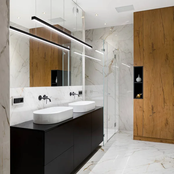 精致的浴室 白色大理石瓷砖铺在地板和墙壁上 在两个椭圆形的洗脸盆下装有黑色抽屉箱 — 图库照片