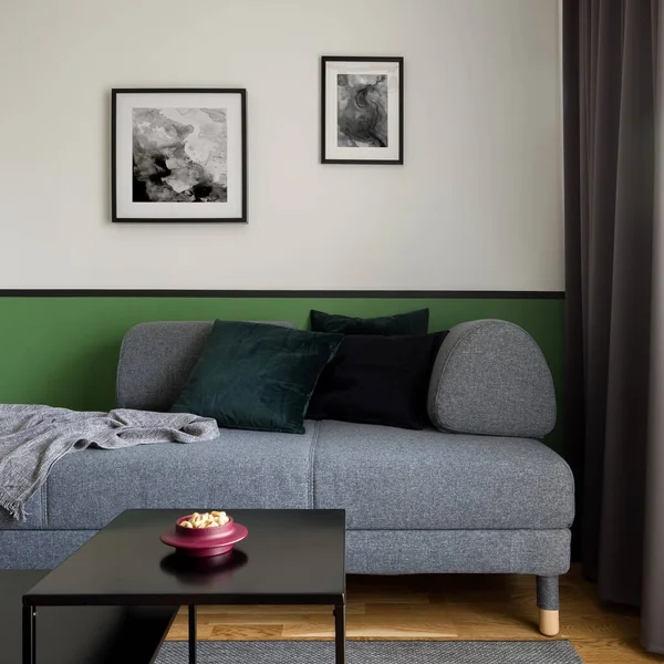 Living room with simple and stylish gray sofa and two black coffee tables on gray carpet