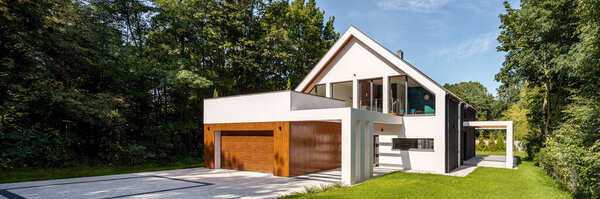 Элегантный белый дом с деревянным фасадом на гараже, брусчаткой и зеленым садом
