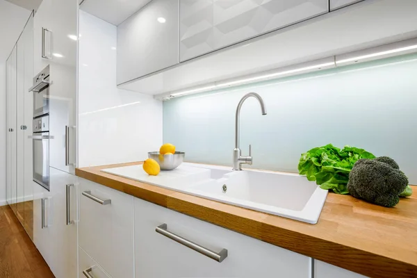 Stylish white furniture kitchen with simple sink in wooden countertop