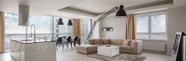 Mutfak ve yemek salonunun panoraması şehir manzaralı, inanılmaz bir şekilde tasarlanmış bir dairede oturma odasına açık.