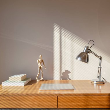 Kitap, lamba, bilgisayar ve dekoratif ahşap adamla çalışmak için basit ahşap masa.