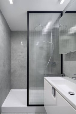 Gri fayanslı modern banyo ve endüstriyel stil güçlendirilmiş cam duvarın arkasında duş.