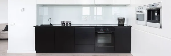 Panorama of modern and simple designed kitchen interior with black and white furniture