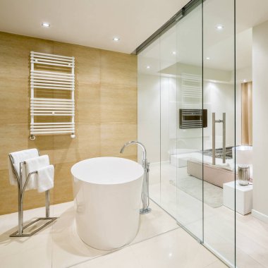 Küveti olan şık bir banyo ve cam duvarın arkasında şık bir yatak odası.