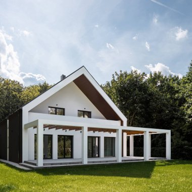 Modern beyaz ev, şık teras ve yeşil çimenlik dış görünüme sahip.