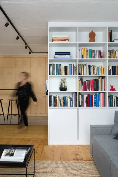 白い本棚 木製の床とコンクリート天井のスタイリッシュなアパートの女性 — ストック写真