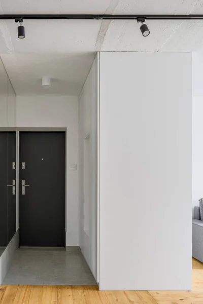 Simple white apartment corridor with mirror wall, black doors and concrete ceiling